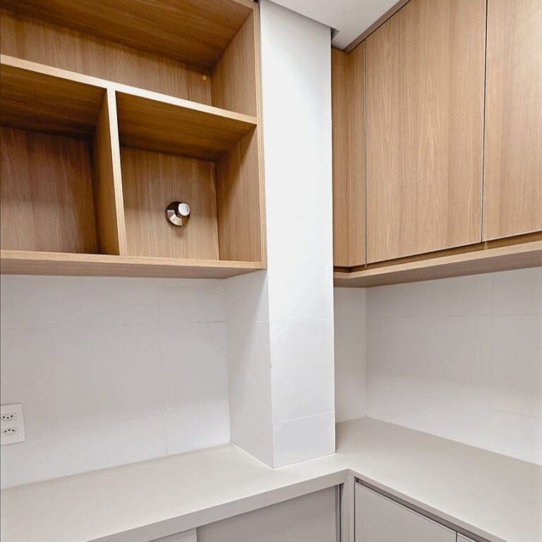 Armários de cozinha planejada em marcenaria clara com puxadores discretos na cozinha reformada do apartamento no Buritis.