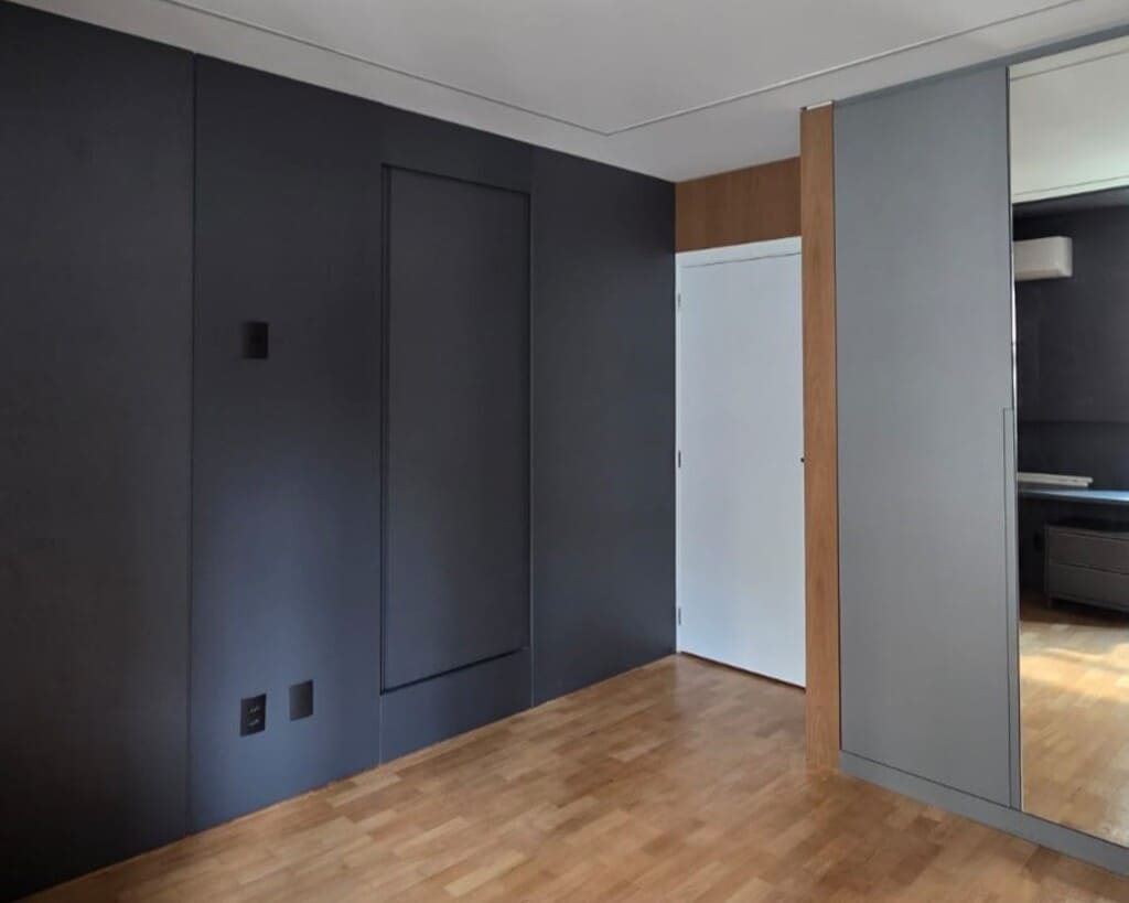 Corredor com painéis em grafite e iluminação indireta no teto.