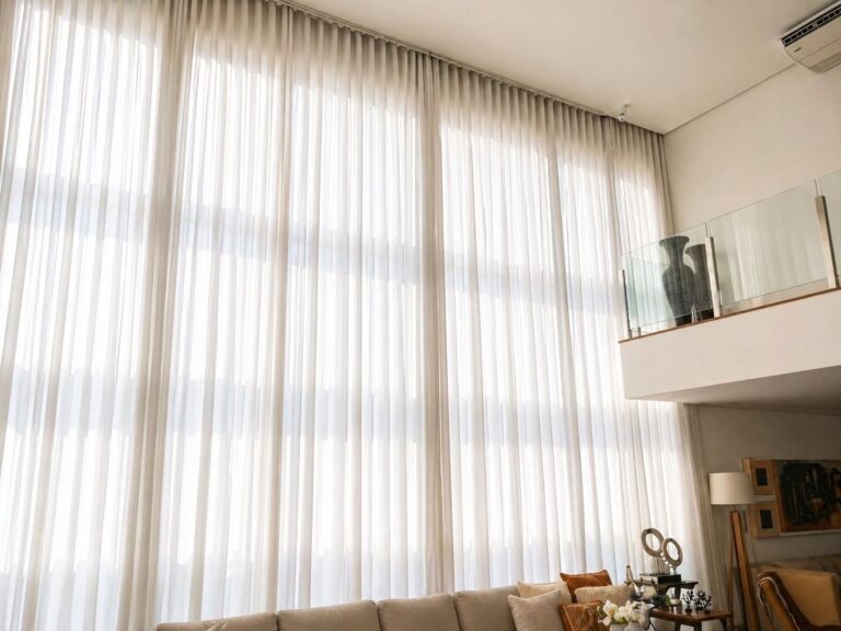 Sala com pé-direito duplo e cortinas altas com iluminação natural